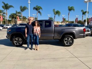 man and woman standing in front of gray truck