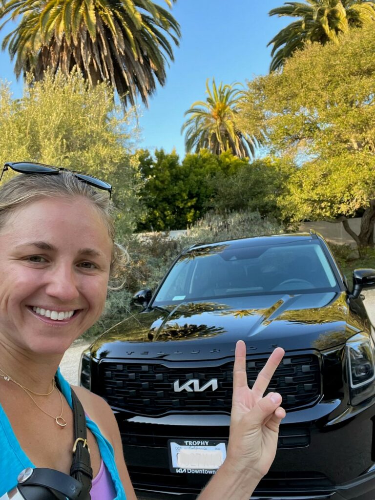 woman next to her car with peace sign held up